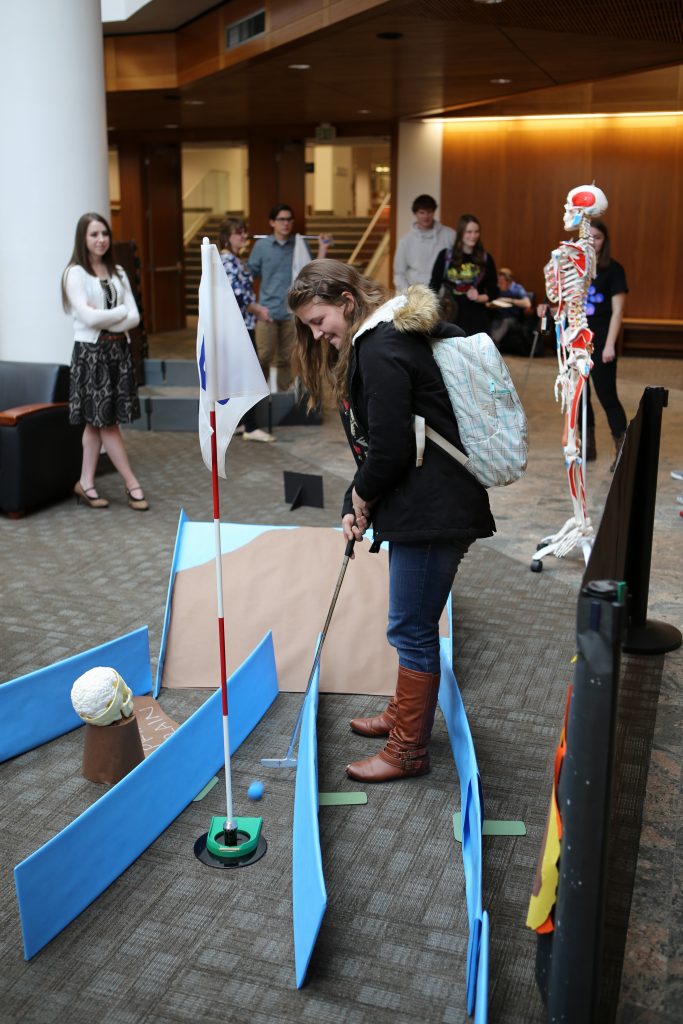 A student plays mini-golf in the library atrium during last year's "Love Your Library Week." This year's mini-golf holes will be specially designed by various library departments to showcase what they have to offer. (Roger Layton)