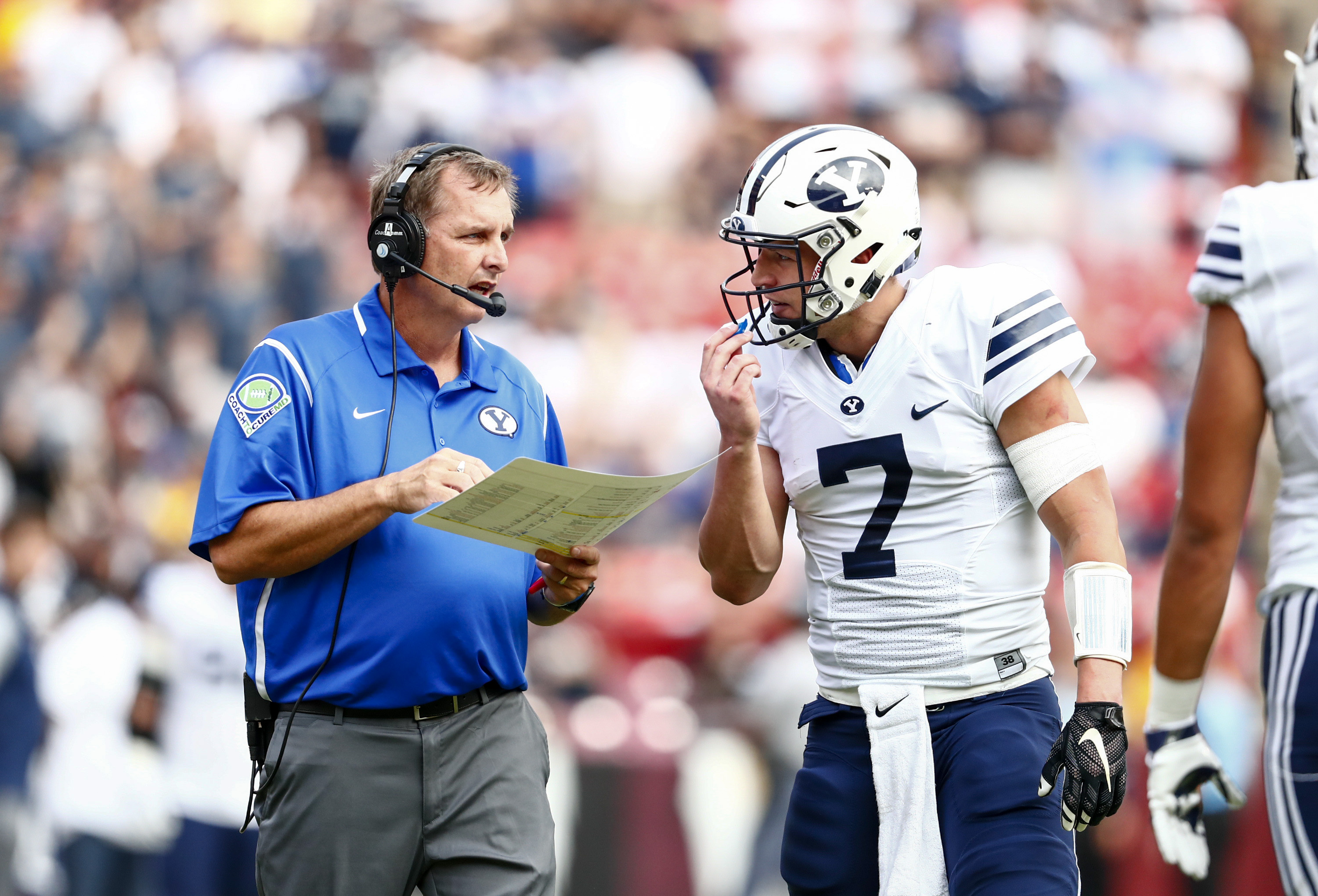 Offensive coordinator Ty Detmer discusses a play call with quarterback Taysom Hill. (BYU Photo)