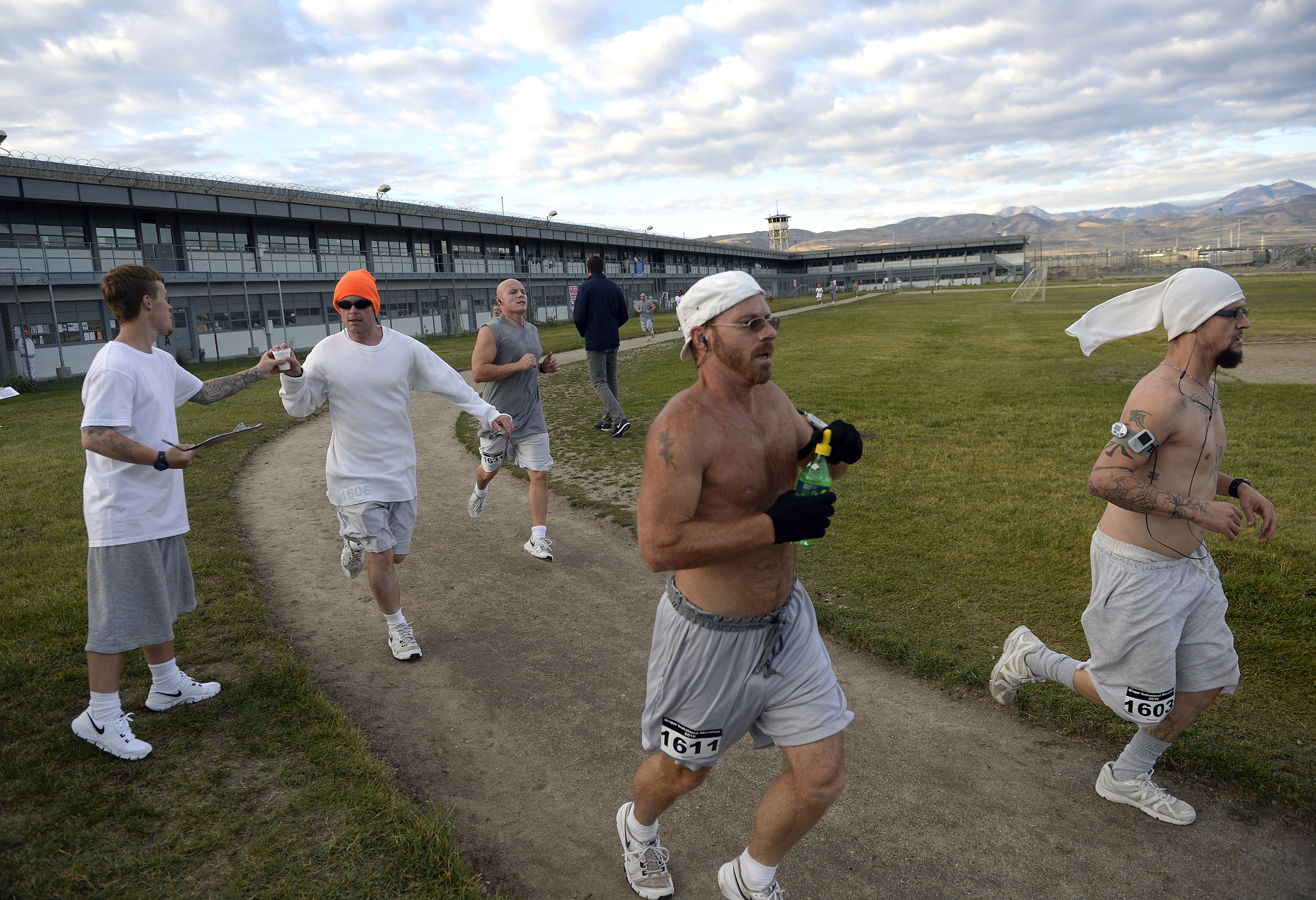 Inmates at the Utah State Prison in Draper, Utah, run the enclosed exercise yard-track at the start of the Draper Invitational Marathon, Half-Marathon and 10K races Tuesday, Oct. 25 2016. A group of frontrunners grab some water and stick together for the first part of the race. Full marathon runners will run 110 laps around the track. (Al Hartmann/Salt Lake Tribune via AP)