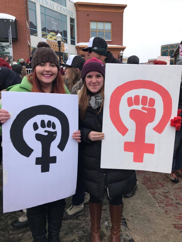 Roma Jones attends the march with a friend bearing signs to promote female rights.