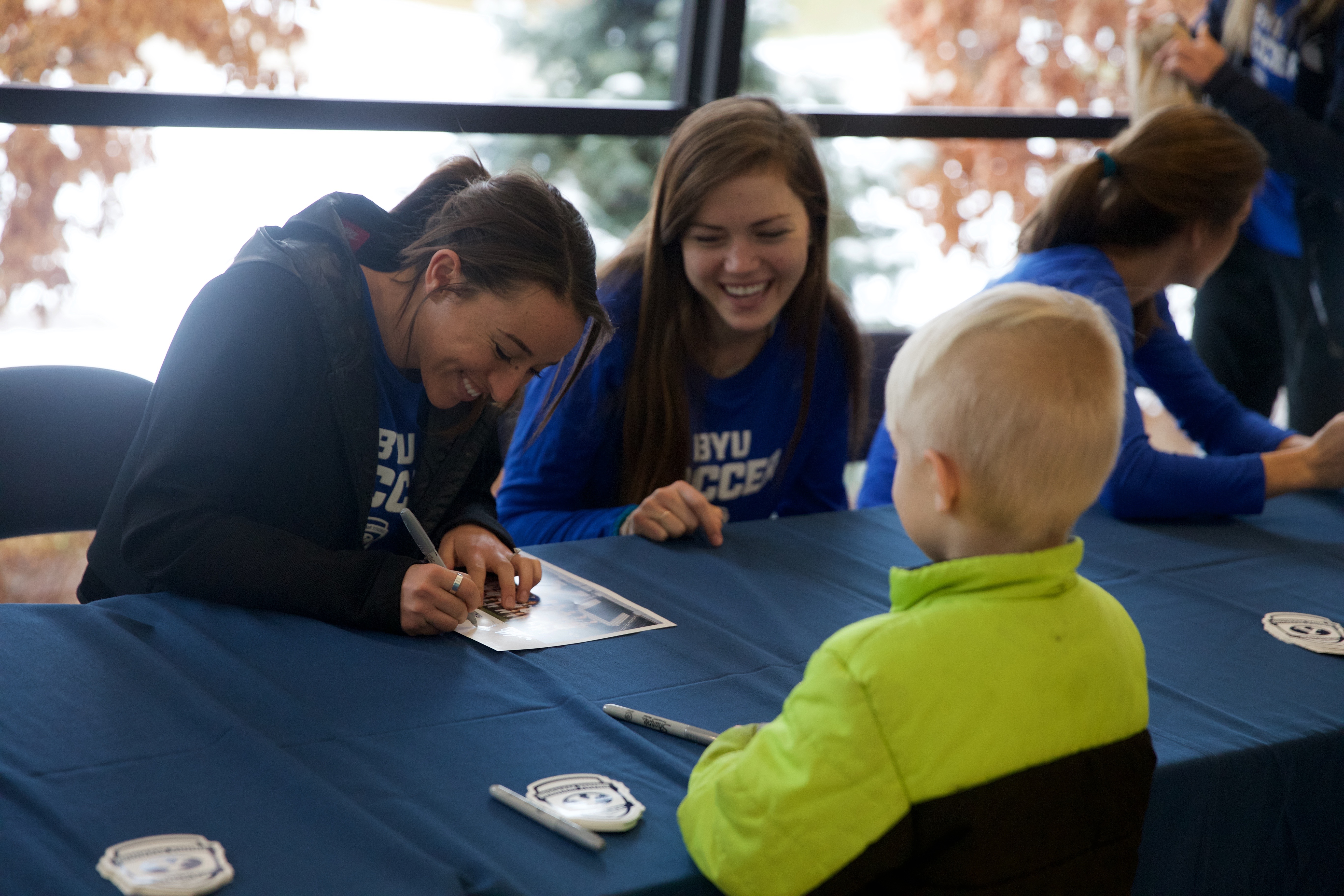 Members of the BYU women's soccer team signs autographs for a young fan. (Maddi Driggs)